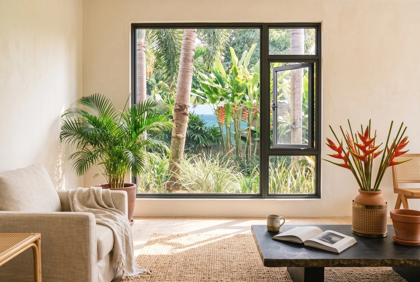 A casement window open onto a shaded terrace and the sea beyond